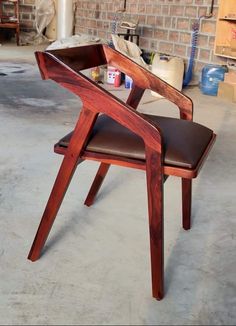 a wooden chair sitting on top of a cement floor next to a brick wall in a garage