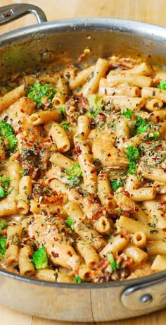 a pan filled with pasta and broccoli on top of a wooden table