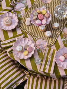 a table topped with plates and cups filled with desserts on top of striped napkins