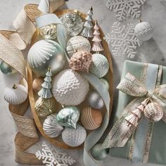 an assortment of christmas ornaments and gifts on a marble surface with snowflakes in the background