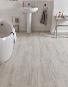 a bathroom with white fixtures and wood flooring on the walls, along with a bathtub