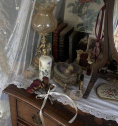 there is a dresser with many items on it and a candle in front of the mirror