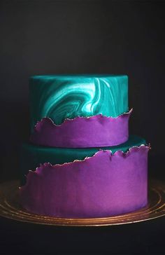 two purple and green cakes sitting on top of each other