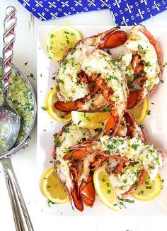 a white plate topped with cooked lobster and lemon wedges