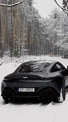 a black sports car parked on the side of a snow covered road in front of trees