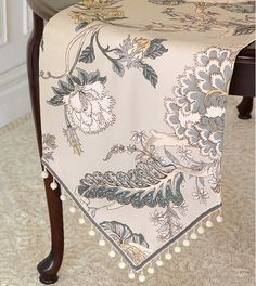 a table with a white and blue floral design on it, sitting next to a chair