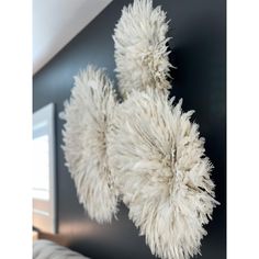 two white fluffy balls hanging from the ceiling in a room with black walls and flooring