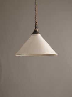 a white light hanging from a brown cord on a gray wall in an empty room