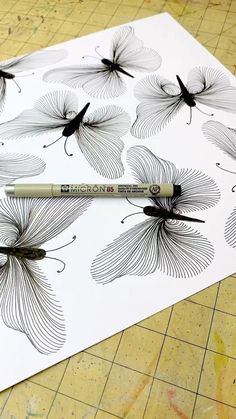 a pencil is sitting on top of a drawing paper with black and white flower designs