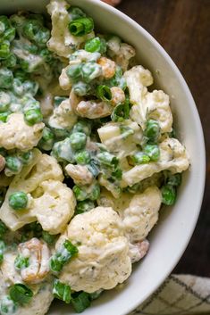 a white bowl filled with cauliflower and peas