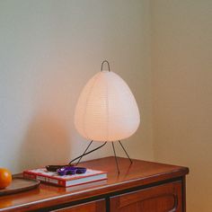 a lamp sitting on top of a wooden dresser next to an orange and some books