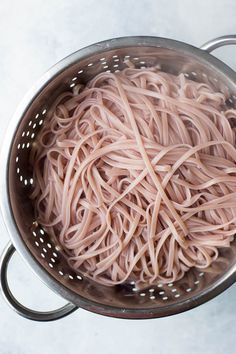 a large metal colander filled with noodles