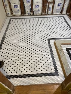 the floor is covered in black and white tiles, with bags of cement next to it