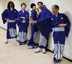 four men in blue and white kimonos standing against a wall with their arms crossed