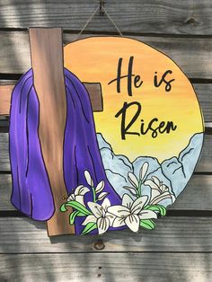 a wooden sign that says he is risen with flowers and a cross hanging from it