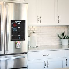 a kitchen with white cabinets and stainless steel appliances, including a large chalkboard on the refrigerator