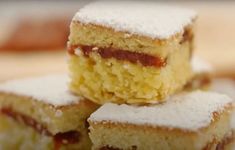 four pieces of cake sitting on top of a white plate covered in powdered sugar