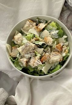 a white bowl filled with salad sitting on top of a bed next to a teddy bear