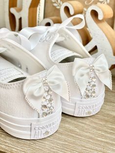 two pairs of white shoes with bows on them