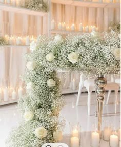 a wedding arch with flowers and candles on the floor in front of a white chair