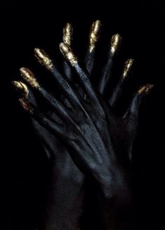 two hands with black and gold painted on them