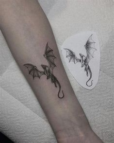 a small dragon tattoo on the left inner forearm and wrist, with wings spread out