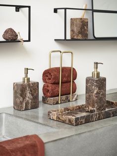 a bathroom with marble and gold accessories on the counter top, including soap dispensers