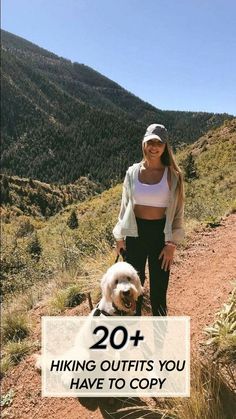 a woman standing on top of a dirt road next to a white and brown dog