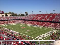 an empty football stadium with red seats and fans in the stands looking out over the field