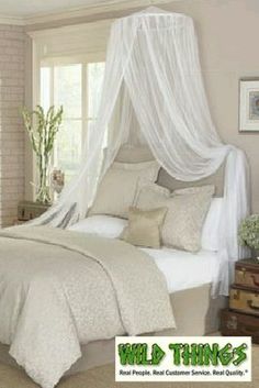 an image of a bedroom setting with white bedding and curtains on the windowsill