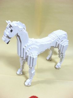 a white horse made out of legos on a table next to a red object