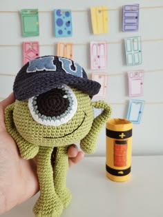 a hand holding a small stuffed animal in front of a wall with magnets on it