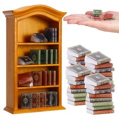 a person holding out their hand next to a book case with stacks of books on it