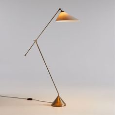 a floor lamp with a white shade on the top and a black cord attached to it