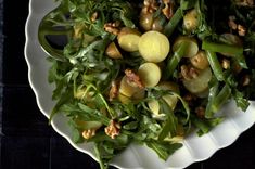 a white bowl filled with green vegetables and nuts