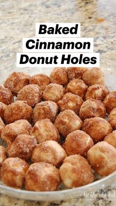 a glass bowl filled with sugared donuts on top of a marble countertop