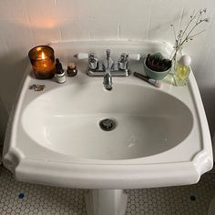 a white bathroom sink sitting next to a toilet and a wall mounted faucet