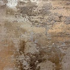 an old dirty wall with some brown and white paint on it's surface,