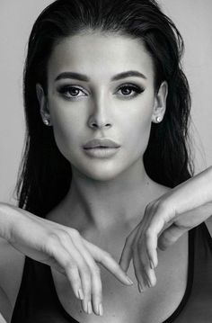 a black and white photo of a woman with her hands on her chest, looking at the camera