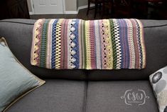 a crocheted pillow sitting on top of a gray couch