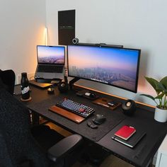 two computer monitors sitting on top of a desk next to a keyboard, mouse and cell phone