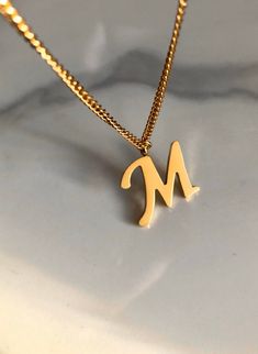 Letter M necklace, set on a stainless steel ,golden color chain. Chain length 19'  With addition cost there is an option to add a white freshwater pearl, as a charm, next to the letter. 6 mm, white round pearl Kindly choose your option. Beautiful spiritual gift. Please make sure you to pay attention to the size of the pendant. I have added pictures next to 25 cent coin, and measurement tape.  Need a different length just write it to me in the "message to the seller" box of the order form. **LIMI Minimalist Stainless Steel Name Necklace, Gold Initial Necklace In Stainless Steel, Stainless Steel Initials Name Necklace, Gold Stainless Steel Initial Necklace, Minimalist Gold Stainless Steel Name Necklace, Gold Dainty Stainless Steel Name Necklace, Dainty Gold Stainless Steel Name Necklace, Elegant Initials Necklace In Stainless Steel, Elegant Stainless Steel Initial Pendant Necklace