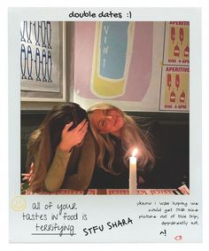 two women sitting next to each other in front of a candle