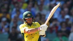 a man in green and yellow uniform swinging a bat at a ball while people watch from the stands