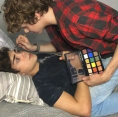 two young people laying on a bed with a rubix cube in front of them