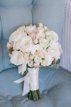 a bridal bouquet sitting on top of a blue chair next to a white pillow