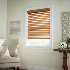 a white chair sitting in front of a window with wooden blinds on top of it