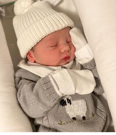 a baby sleeping in a white and grey outfit