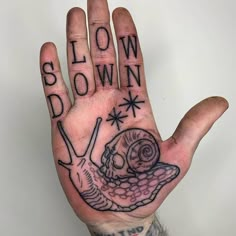 a person's hand with the words slow down on it and a snail tattoo