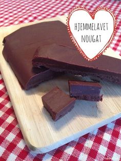 some pieces of chocolate on a wooden cutting board with a heart shaped sign above it